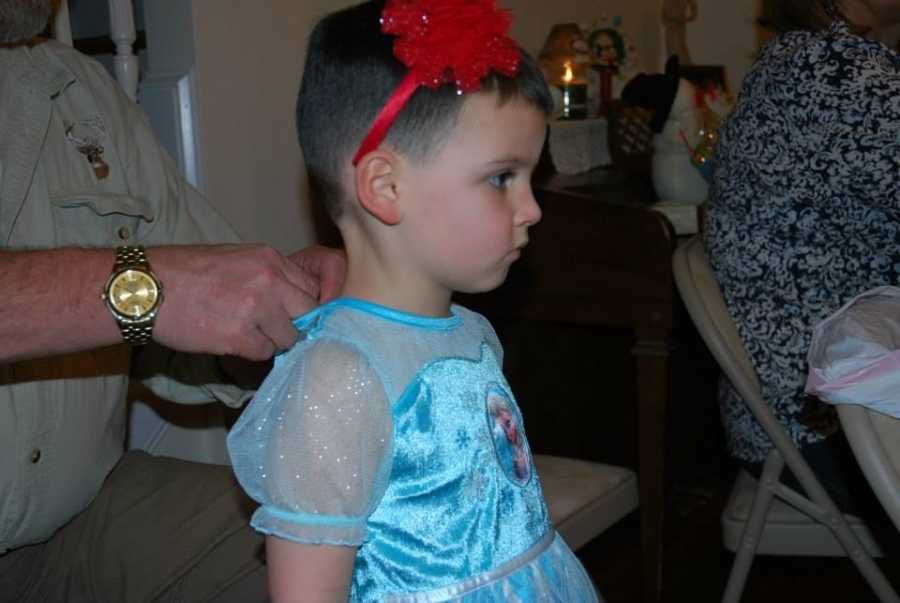 Little boy who wants to be a girl wearing princess dress and red headband with bow