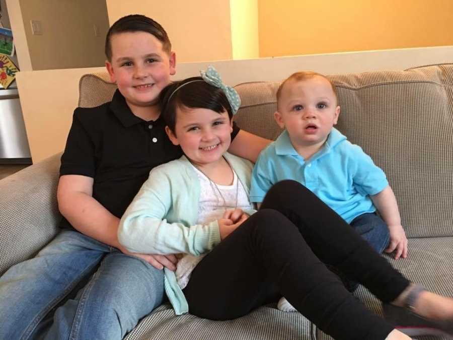 Little boy who became girl sits on couch with older and younger brother