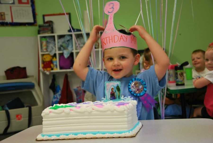 Little boy who wants to be a girl sitting in classroom wearing birthday crown and cake in front of him