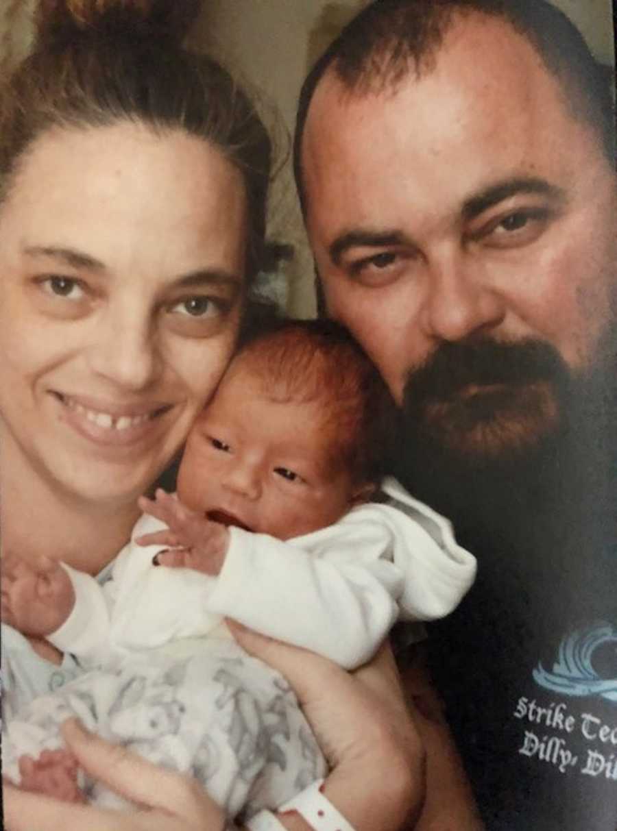 Husband and wife smile as they hold their newborn close to their face