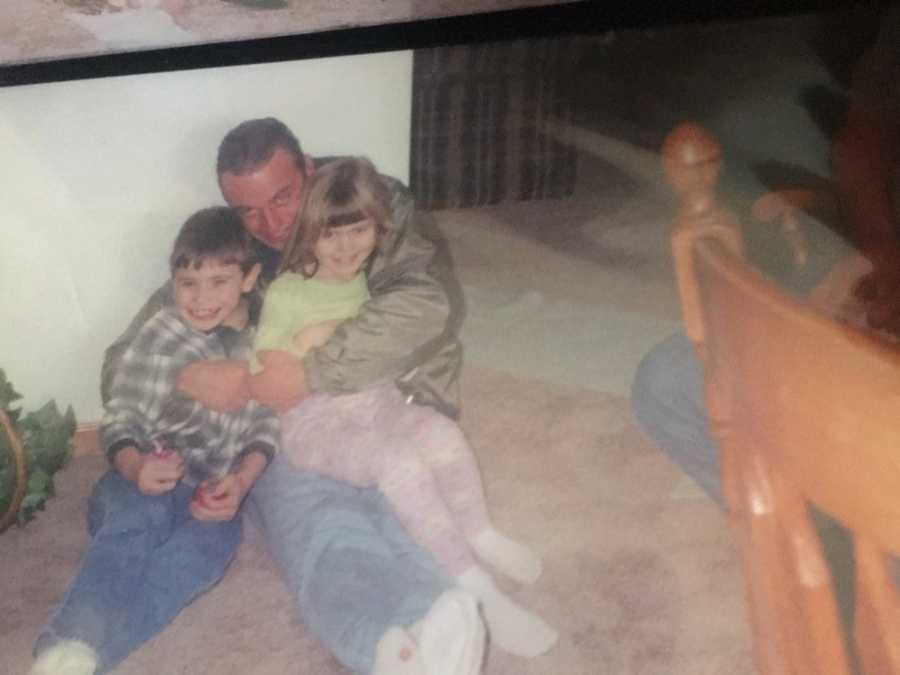 Father who suffered with addiction and committed suicide sits on floor with son and daughter on his lap