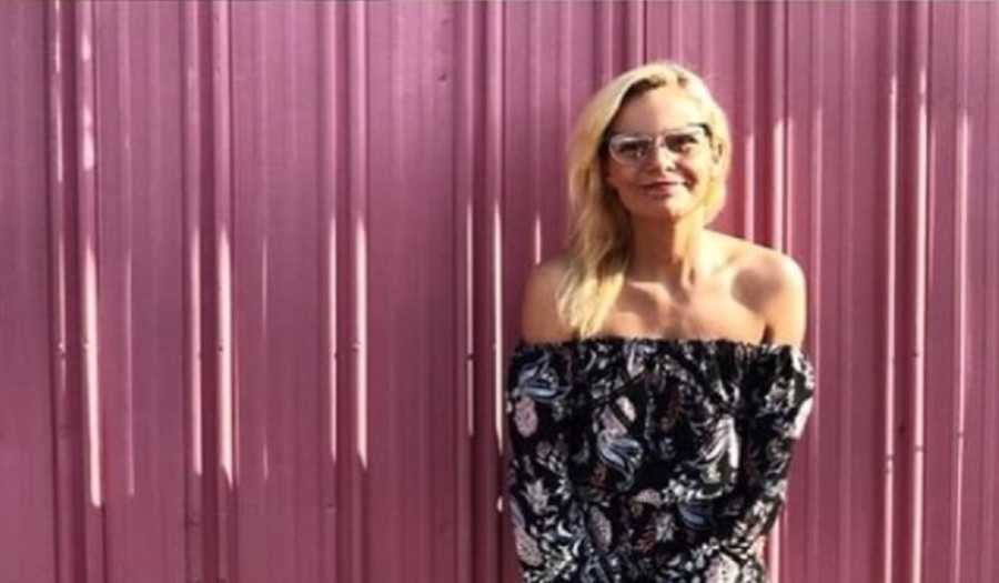 Young woman who decided to get clean and dad committed suicide stands smiling in front of red wall 