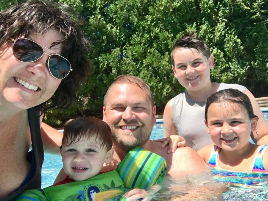 Mother and father stand in pool smiling with three kids one of which almost drown