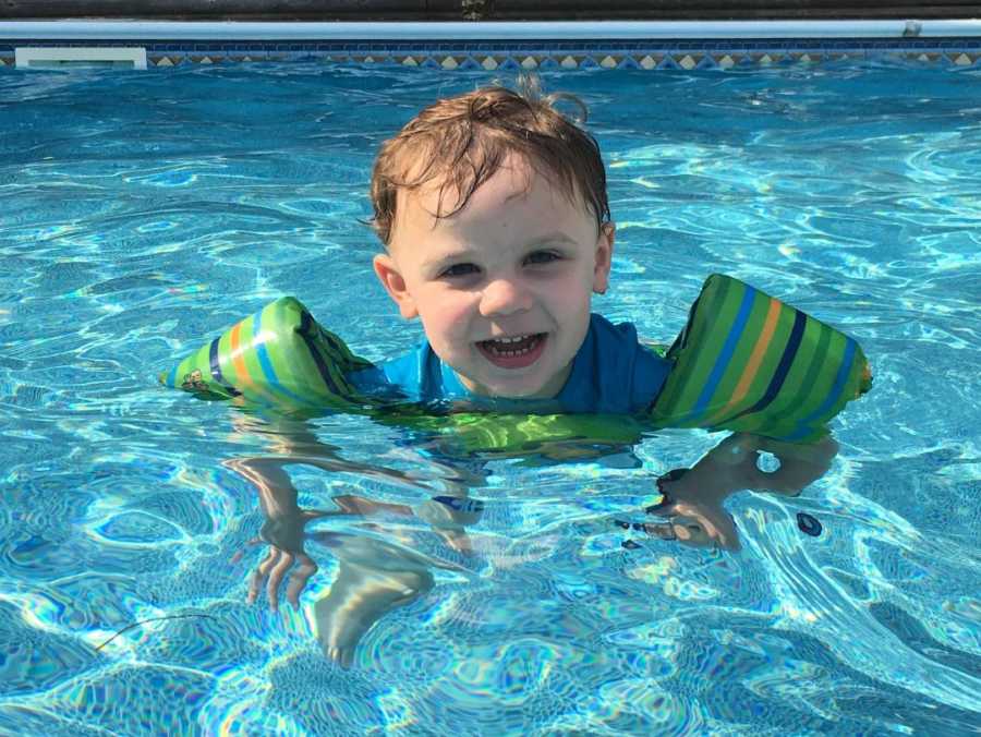 Toddler who almost drown once smiling with floaties on in pool 