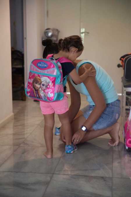 Mother putting on daughters shoe who is starting Pre-K