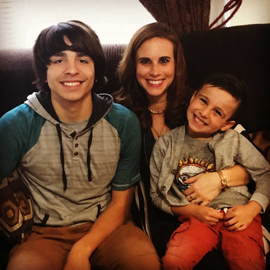 Woman sits with her son and stepson who she treats as son on couch