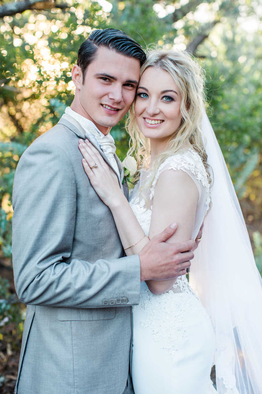 Bride and groom stand chest to chest smiling at wedding on South African reserve