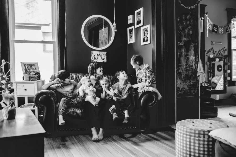 Mom takes a photo with her 5 children while they all sit on a couch together