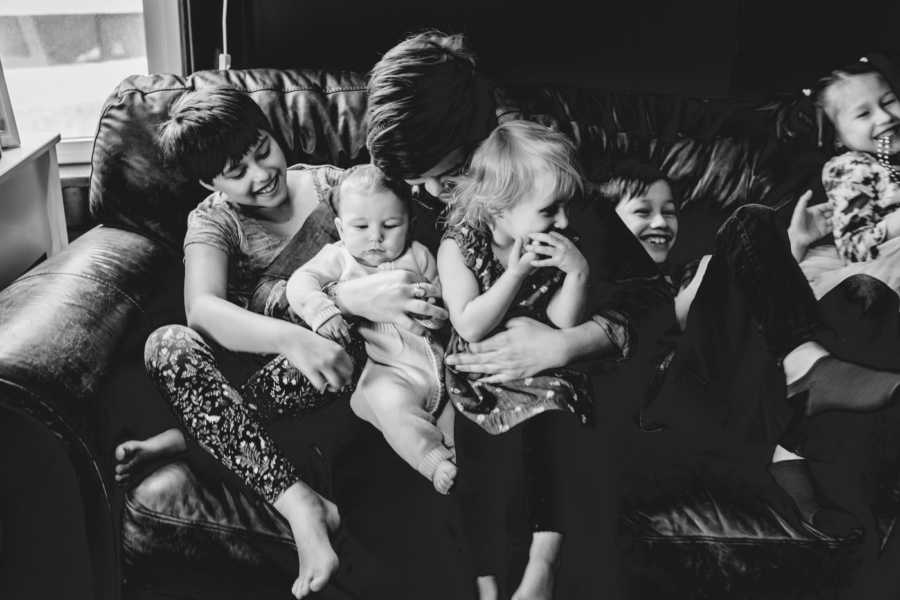 Foster mother sits on couch with five foster kids