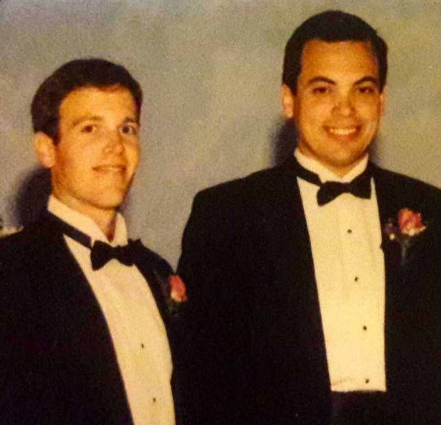 Childhood friends stand smiling in tuxedos at prom