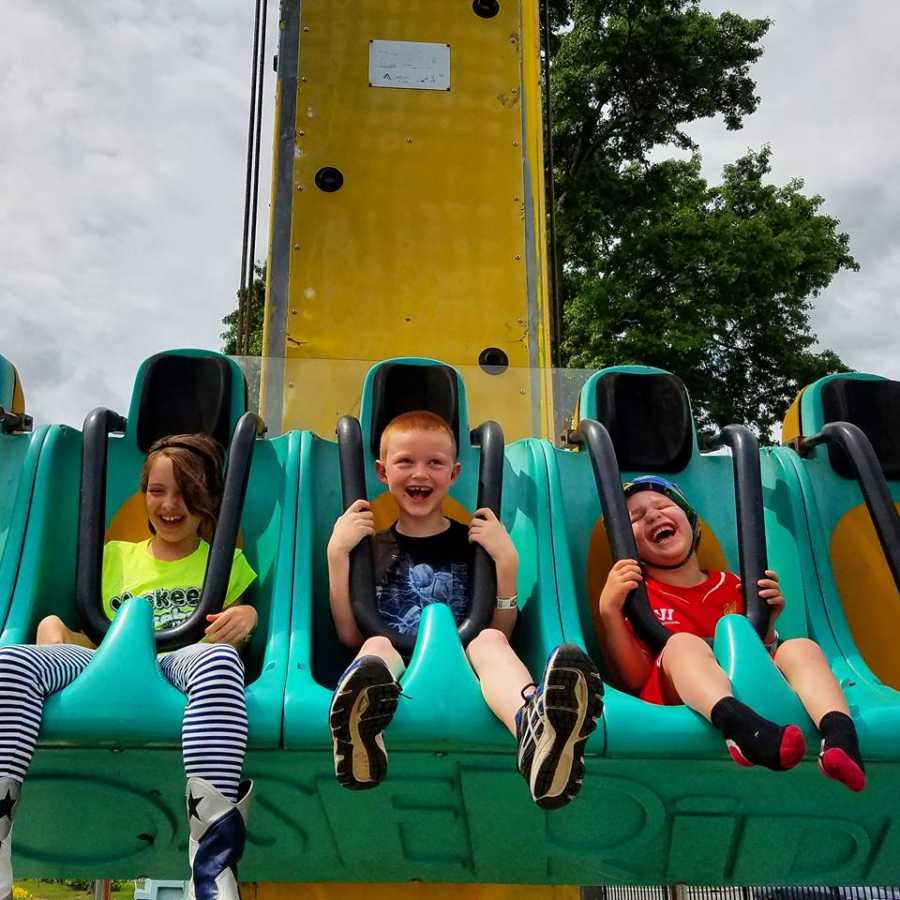 Boy with vanishing white matter disease sits on carnival ride beside brother and sister