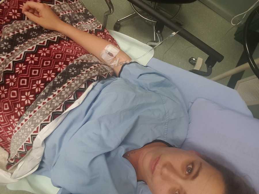 Selfie of woman in hospital bed with pneumonia with IV in her arm