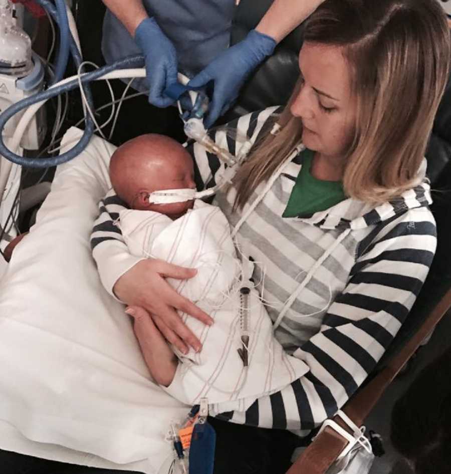 Mother sits in chair holding baby in NICU who didn't make it