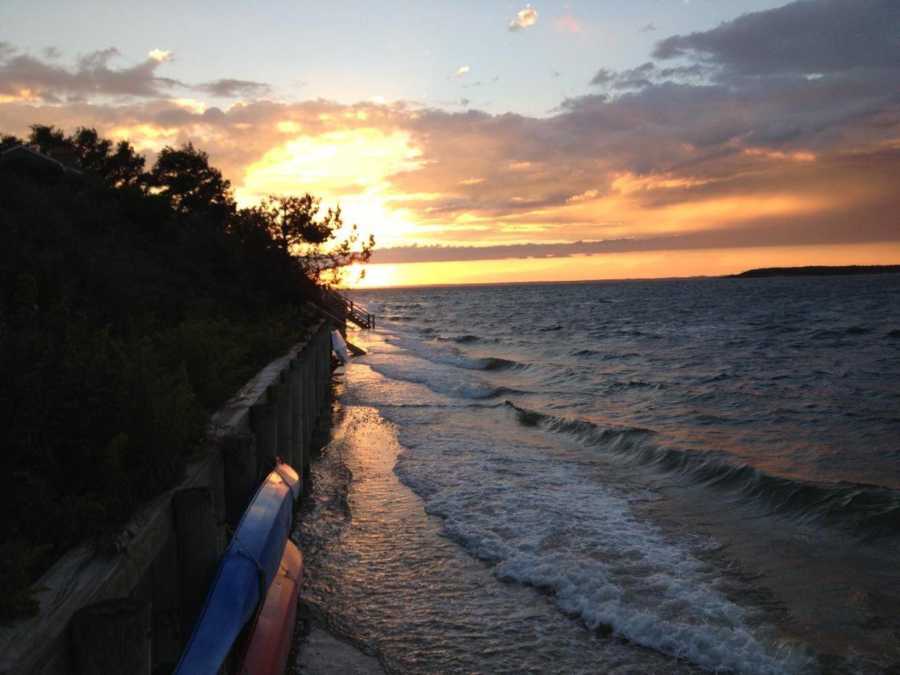 Waves crashing against sea wall at sunset