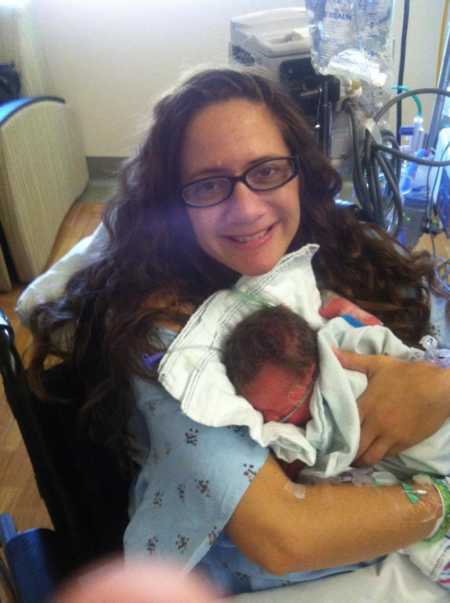 Woman who just gave birth hold's one of her triplets in her arms