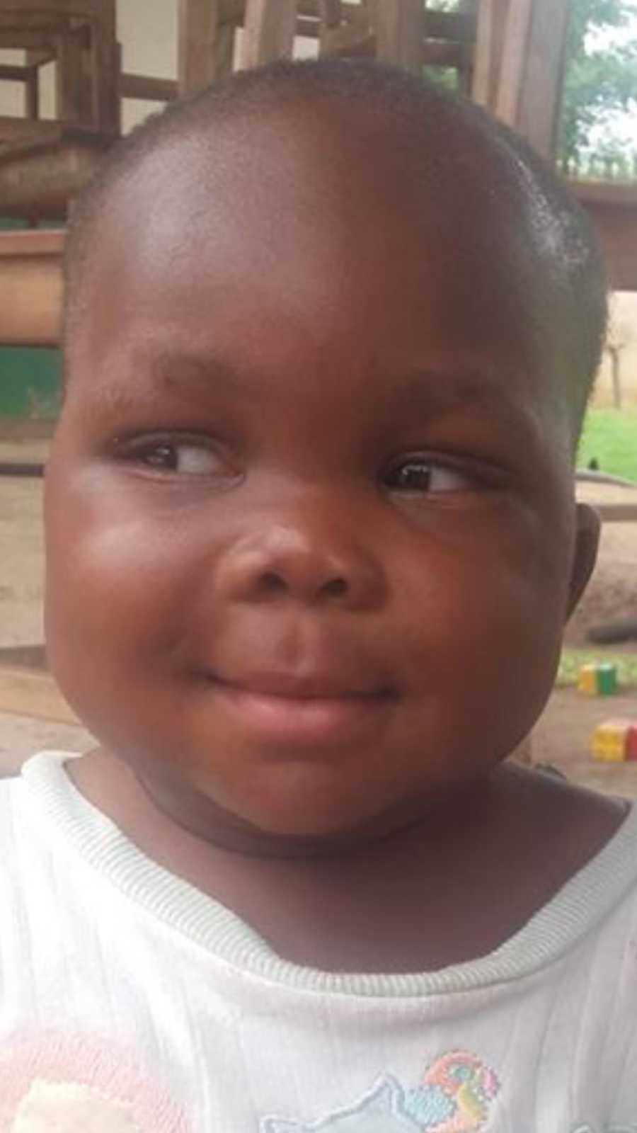 Toddler orphan from African smiling as her eyes look to the side