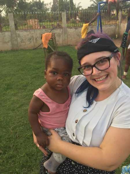 Woman smiles while holding adopted daughter from Africa who has HIV