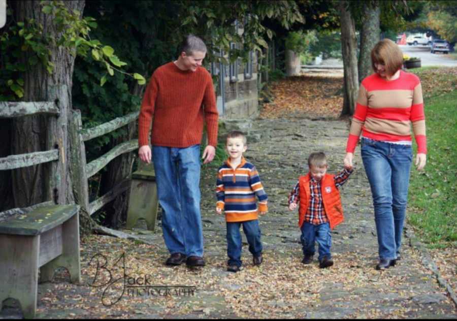 Husband and wife walk on either side of the side walk with their two sons walking between them