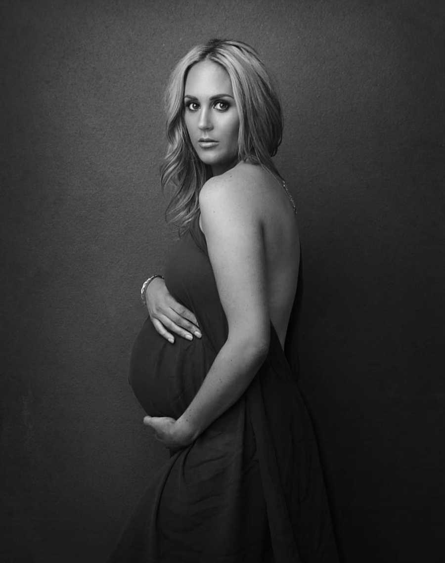 Pregnant mother stands in photoshoot holding stomach