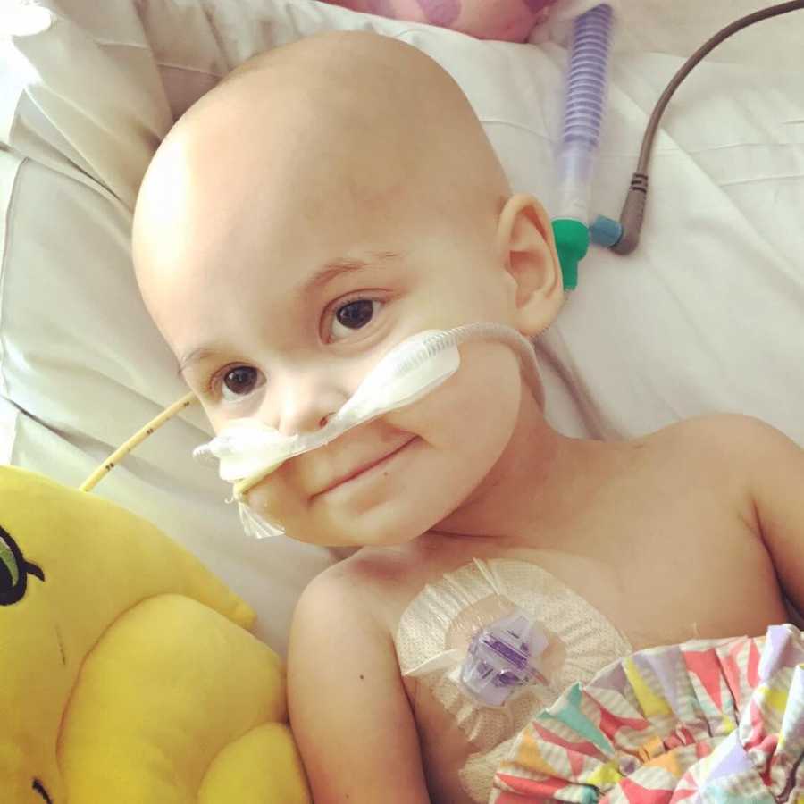 Two year old with Lymphoblastic Lymphoma lying in hospital bed smiling
