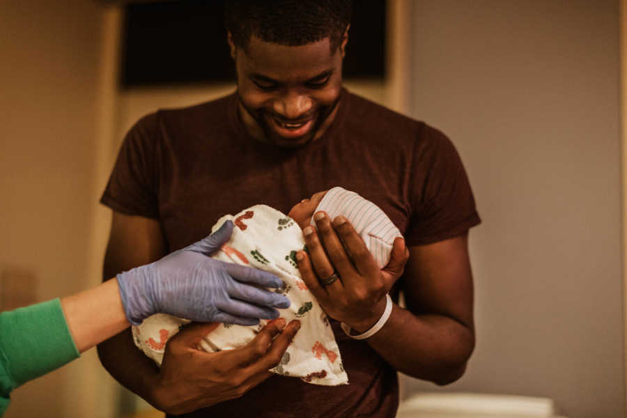 Father smiles down at newborn baby in his arms