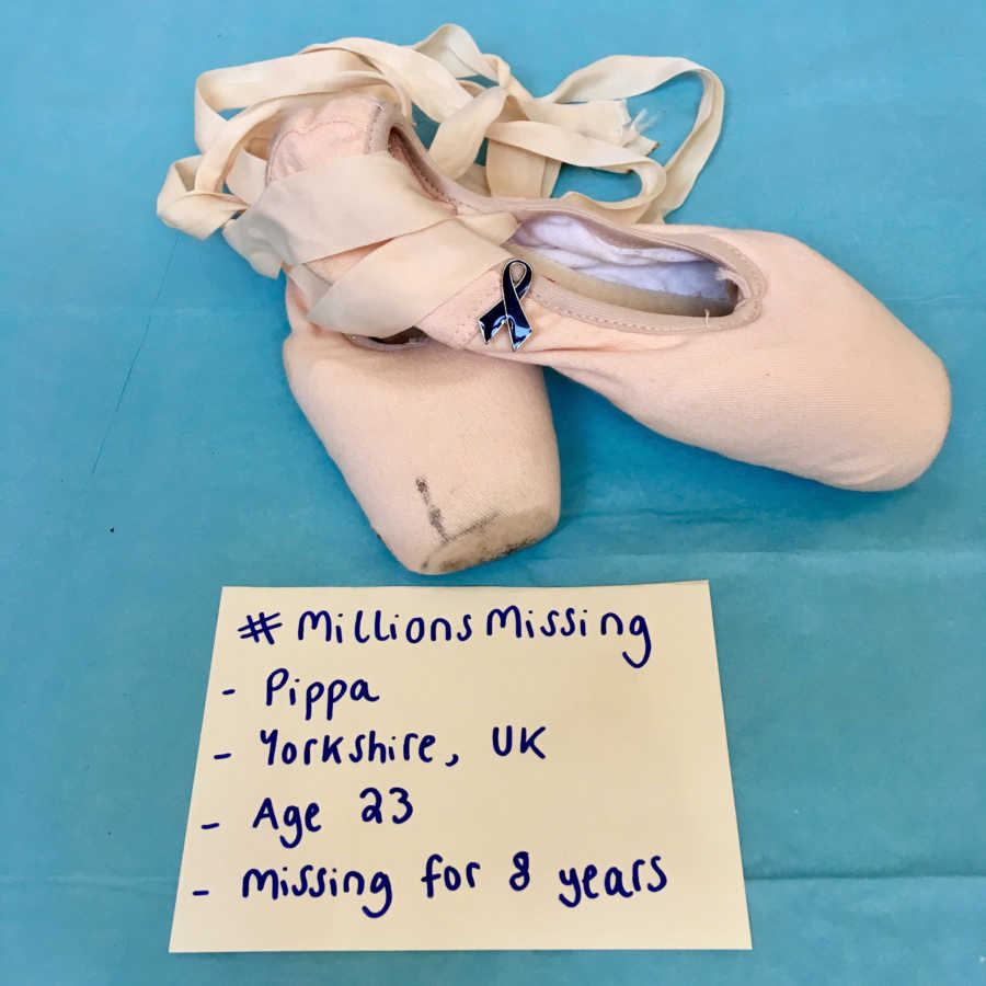 Ballet slippers with black cancer cross pinned to them with note below them saying, "millions missing"