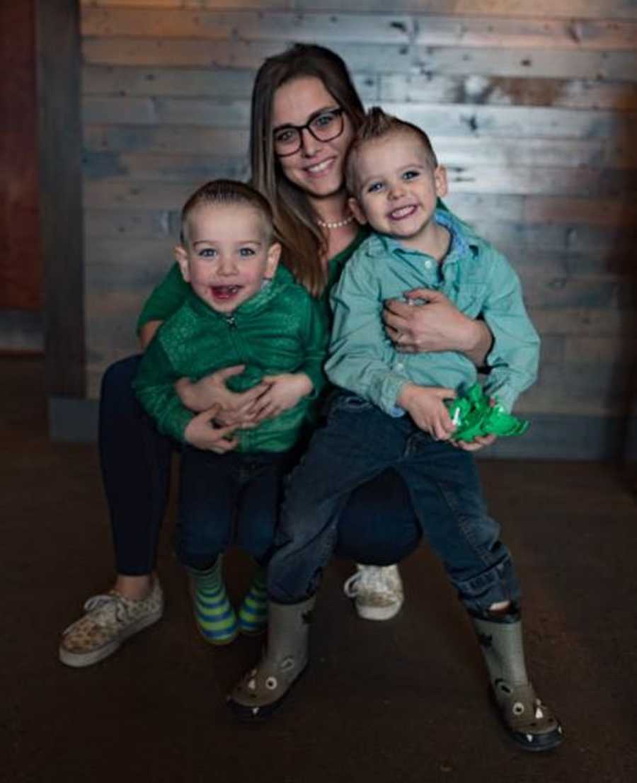 Woman who escaped near death experiences crouches down smiling with her two sons