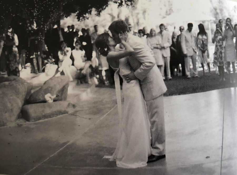 Bride and groom stand kissing at their wedding on dance floor 