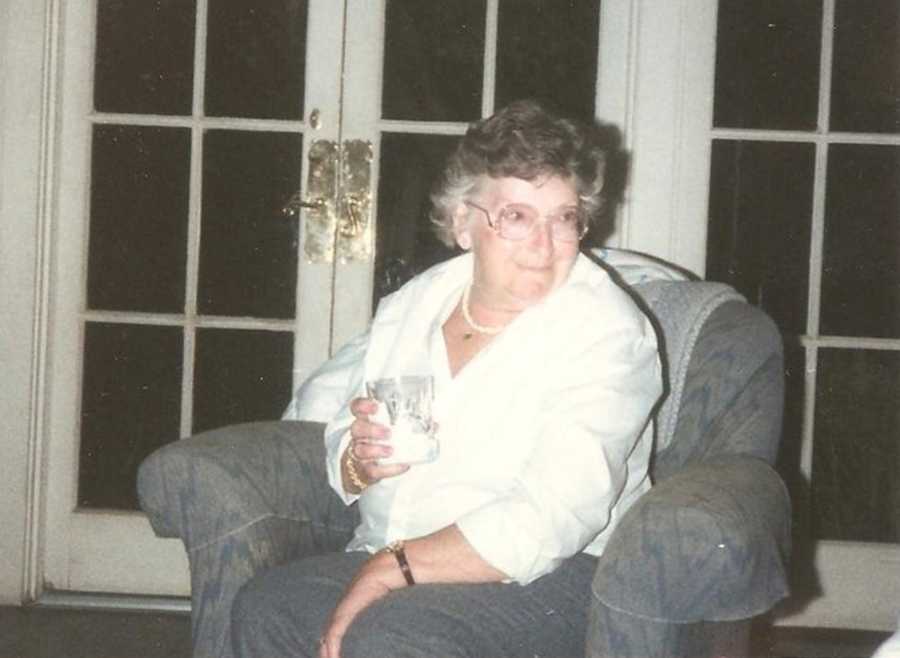 Woman smiling while sitting in chair with cocktail in her hand