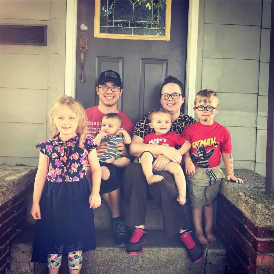 Recovered alcoholic sits on front door steps with girlfriend's kid in his lap beside her and her three other children