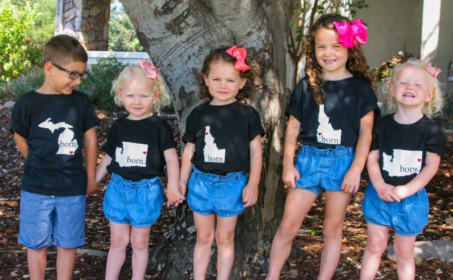 Five siblings stand in front of tree in matching outfits 