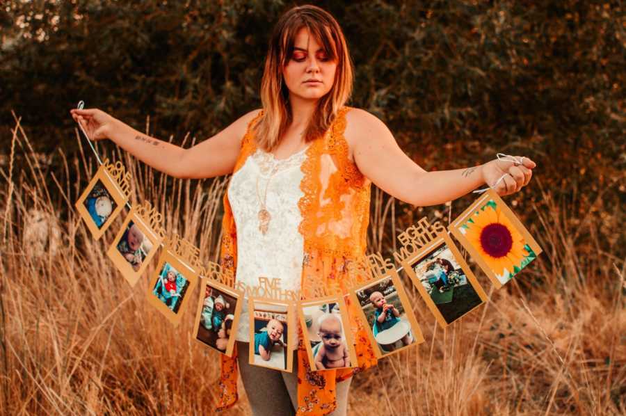 Mother holds strand of pictures from each month she had with her son who passed from SIDS