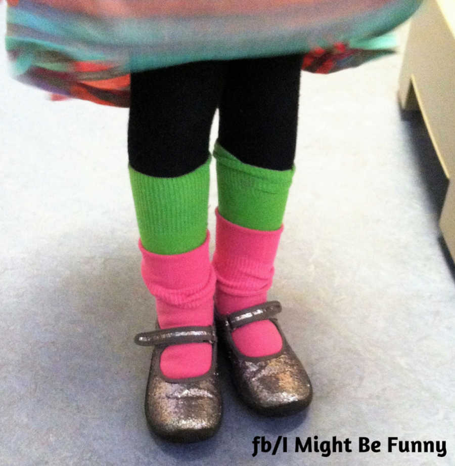 View of little girl's legs who is wearing a pair of bright green and pink socks with fancy shoes