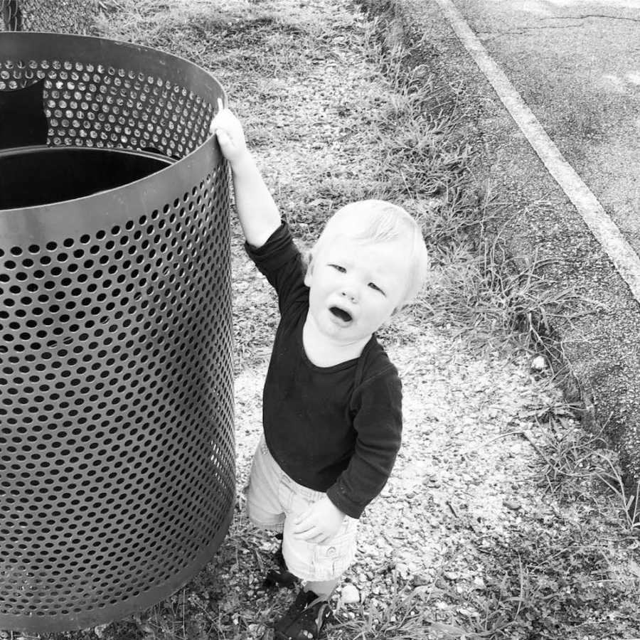 Toddler whose mom says he's well behaved when he's with her stands crying holding on to trash can