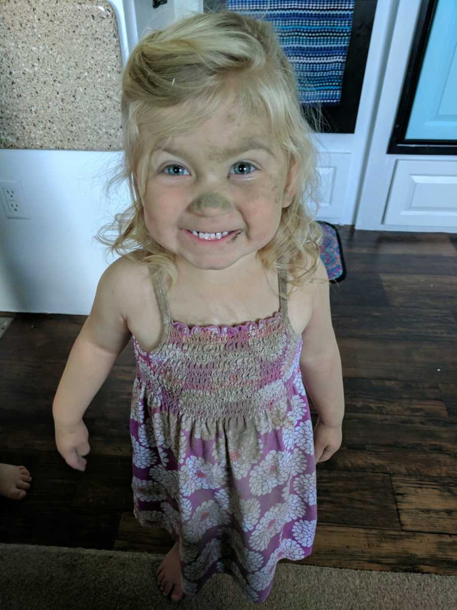 Little girl covered in dirt smiling in the kitchen her mother just cleaned