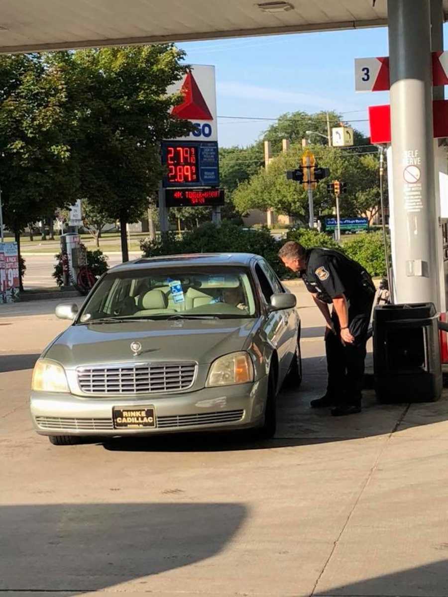 Cop stands besides elderly woman's car at gas station who offered to help her pay for her gas