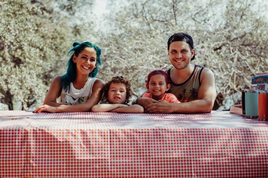 Husband and wife sit at picnic table with their son and daughter in between them