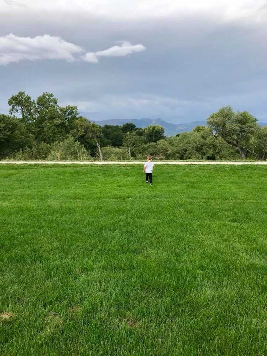 Child walking in grass whose mother tells women they need to put their phone down and pay attention to their children