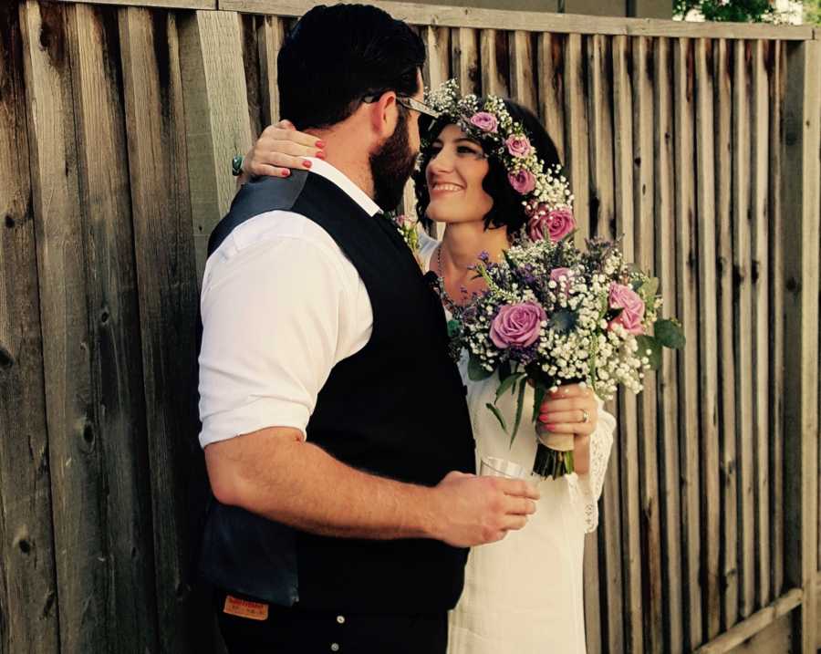 Groom stands arm in arm with bride who has since passed from cancer at wedding ceremony