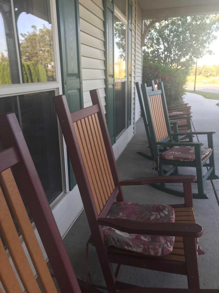 Row of rocking chairs on front porch where elderly woman with dementia likes to sit