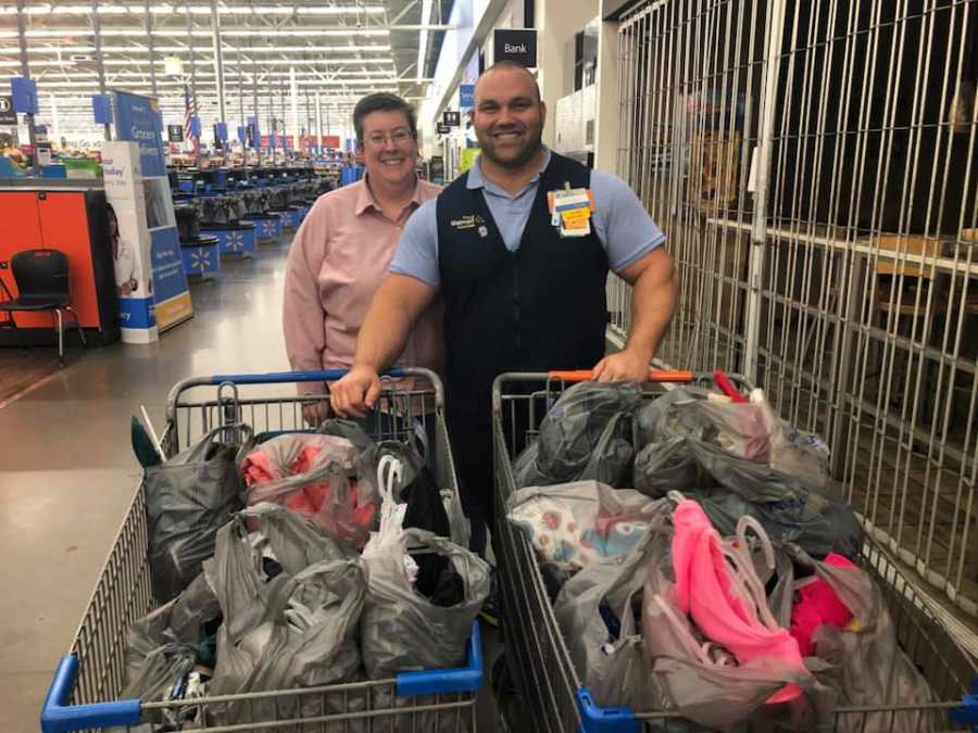 Woman standing beside Walmart manager who stands behind two shopping carts full of items for Hurricane Florence survivors