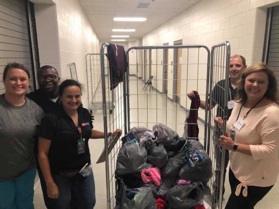 Three women and two men standing on either side of cart filled with bags of donations for Hurricane Florence survivors