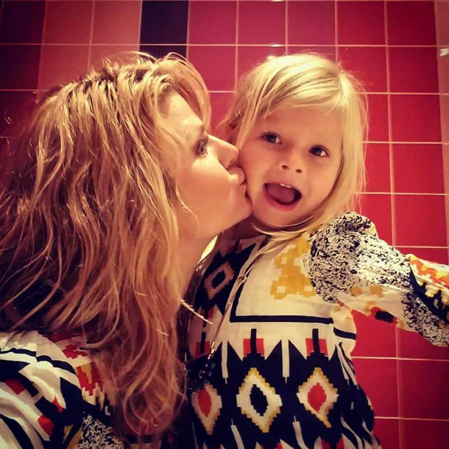 Mother kisses her daughter with sepsis on cheek in selfie while wearing matching outfits