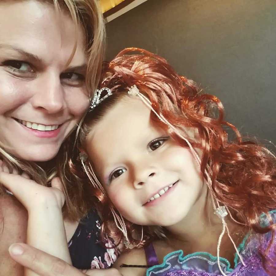 Mother smiles in selfie with her daughter who has sepsis and is dressed in Princess Ariel costume