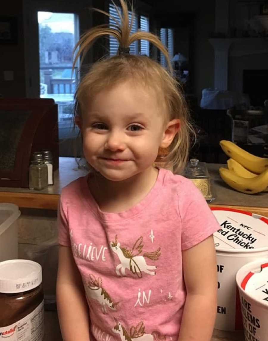 Little girl with undiagnosed diabetes sits smiling on kitchen counter