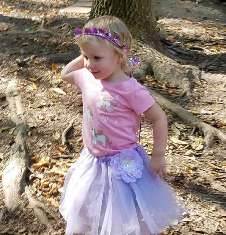 Little girl with undiagnosed diabetes wears tutu and crown outside near tree