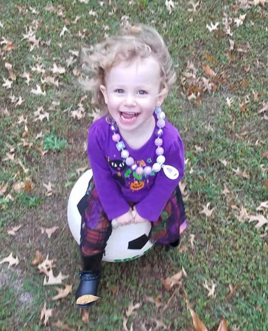 Little girl with undiagnosed diabetes smiling as she sits on soccer ball