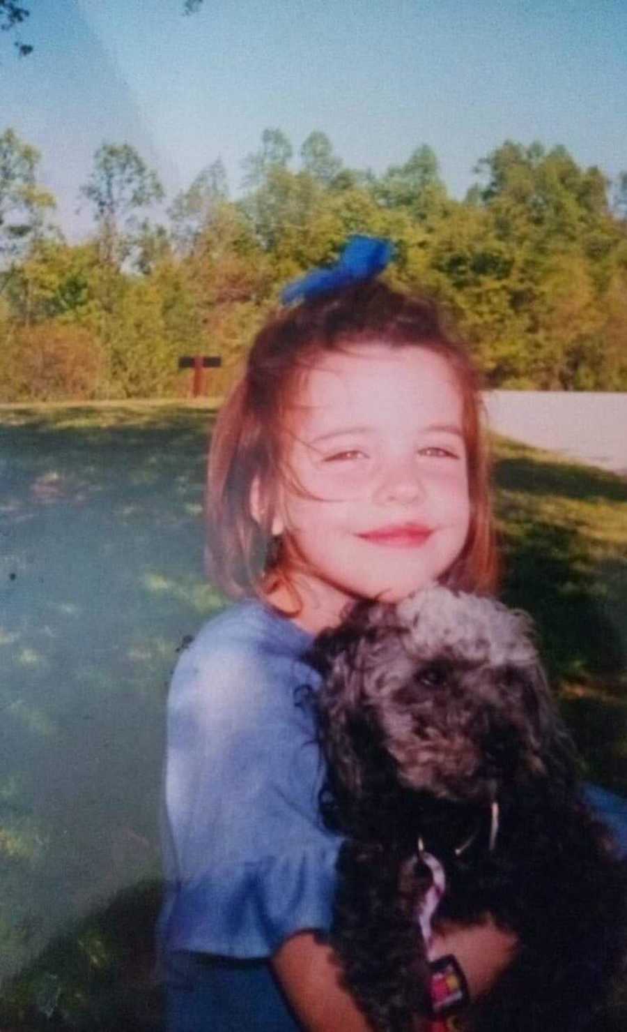 Little girl smiling holding dog who will get raped later in life