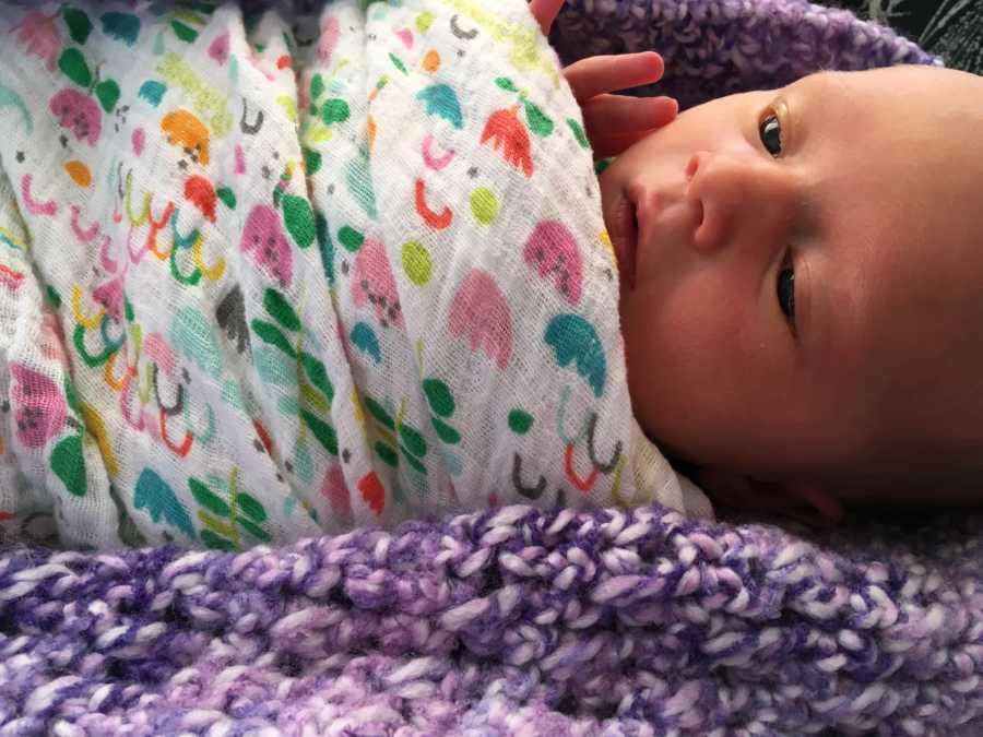 Baby swaddled in blanket laying on purple blanket that belonged to her deceased older sister