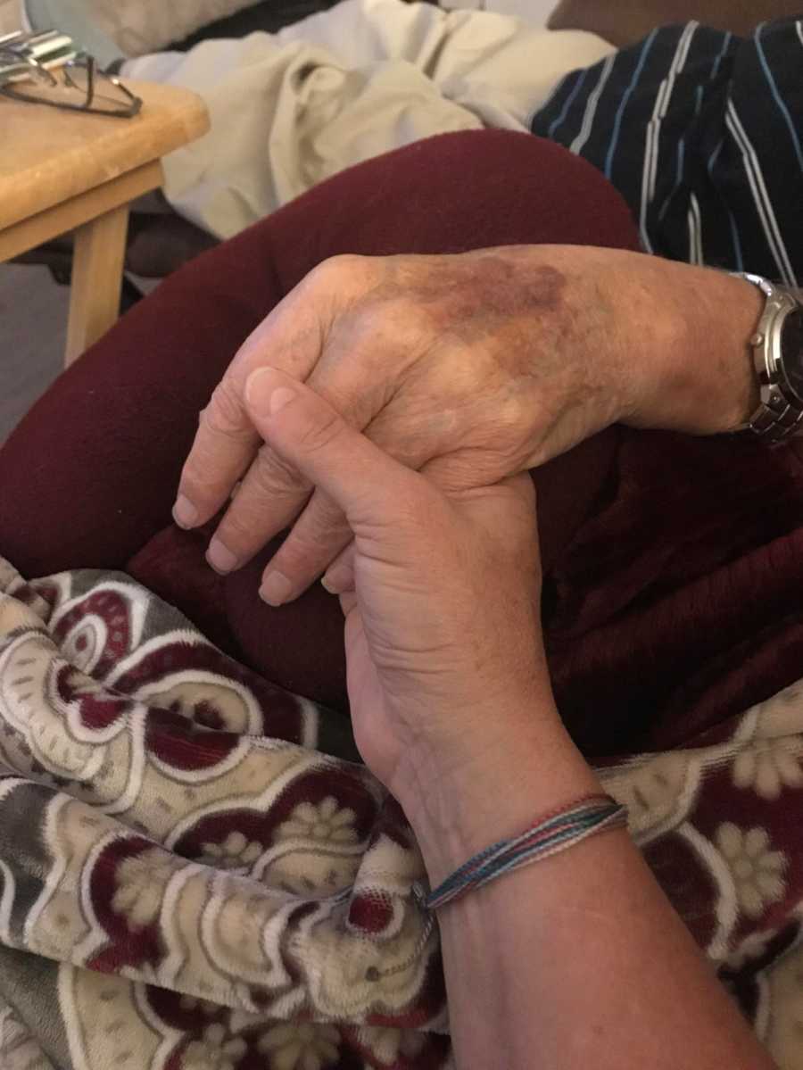 Close up of woman holding mother's hand who has dementia